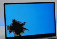 Close-up of a black spot on a Dell laptop screen showing dark irregular LCD damage in lower corner of display